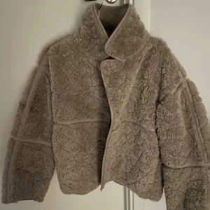 Beige teddyjacka - Mysig beige teddyjacka med knappar framtill. Jackan har en klassisk krage och är perfekt för kyligare dagar. Den är både stilren och bekväm, vilket gör den till ett måste i garderoben.