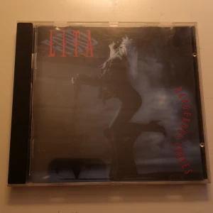 Dangerous Curves CD av Lita - CD-skiva av Lita med titeln 'Dangerous Curves'. CD-skivan är i bra skick 