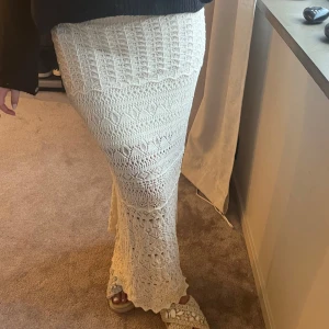 Vit stickad långkjol - Snygg vit stickad/virkad långkjol med ett vackert mönster. Kjolen har en tight passform och är perfekt för en stilren look. Aldrig använd. Har en under kjol på bilderna eftersom den är virkad kan man se igenom 💕