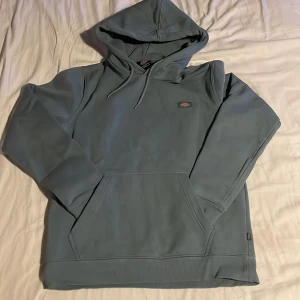 Grön hoodie från Dickies - Säljer en stilren grå hoodie från Dickies i storlek S. Tröjan har en klassisk design med en praktisk magficka och justerbar huva. Perfekt för en avslappnad look. Priset kan ändras om det är för högt.