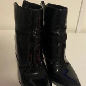 Svarta stövletter från Ecco - Snygga svarta stövletter från Ecco i skinn med dragkedja baktill. De har en spetsig tå och klack, vilket ger en elegant look. Perfekta för att lyfta din outfit med stil.