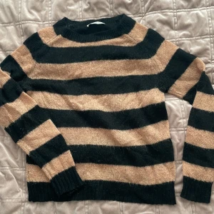 Randig tröja från Normcore - Säljer en snygg randig tröja från Normcore i svart och beige. Tröjan har långa ärmar och är perfekt för en avslappnad stil. Den är gjord i ett mjukt material som känns skönt mot huden.