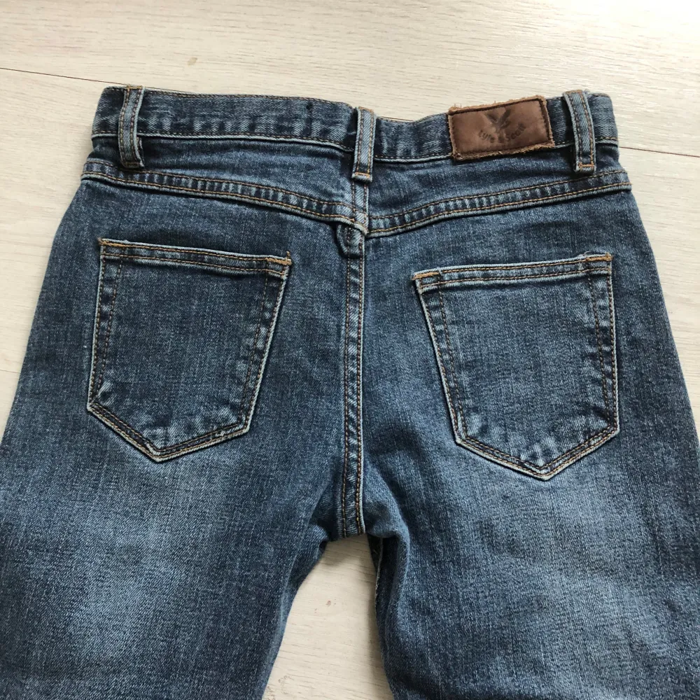 Snygga blå jeans från Lyle & Scott Junior med klassisk femficksdesign. De har en normal passform och är tillverkade i slitstarkt denim. Perfekta för vardagsbruk med en stilren look. Stl 10-11 år, motsvarar ca stl 134. Farkut & Housut.