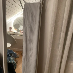 Pärlblå randig klänning - Snygg pärlblå klänning med smala axelband och ett stilrent randigt mönster. Perfekt för en elegant look. Klänningen har en lång design och är tillverkad i ett mjukt material. 