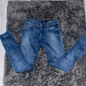 Blå jeans från Replay - Snygga blå jeans från Replay med en klassisk femficksdesign. De har en knappgylf och är i en slim passform som sitter perfekt. Perfekta för en stilren look. Jeansen är slim och storleken är 27 30. priset är dikurterbart och skriv om ni undrar något.