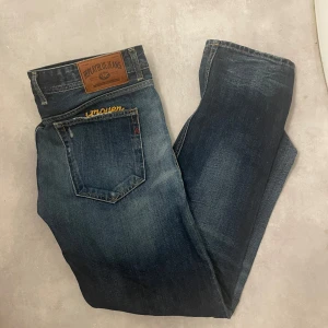 Replay Grover jeans - Snygga blå jeans från Replay, modell Grover. De har en klassisk femficksdesign med slitna detaljer och en knappgylf. Perfekta för en avslappnad stil. Hör av er vid frågor!