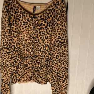 Leopardmönstrad kofta från H&M - Säljer en leopardmönstrad kofta från H&M i storlek 38. Koftan har långa ärmar och knappar framtill.  