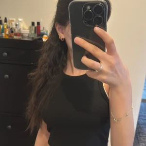 Svart ärmlös topp - Snygg svart ärmlös topp i ett enkelt och stilrent snitt. Perfekt för att matcha med olika outfits. Toppen har en tight passform och är tillverkad i ett mjukt material.