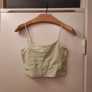 Ljusgrön linnetopp från FB Sister - Säljer en söt ljusgrön linnetopp från FB Sister. Toppen har smala axelband och är croppad, perfekt för varma dagar. Den är tillverkad i ett mjukt material som känns skönt mot huden. Dubbelt tyg så syns inte igenom. Hade svårt att få färgen på kameran, så sista bilden är mest lik den verkliga färgen.