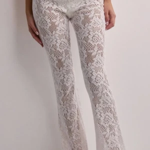 Vita spetsbyxor från Nelly  - Snygga vita byxor i spetsmaterial från Nelly. Byxorna har en tight passform och är lågmidjade, vilket ger en elegant och stilren look. Perfekta för en somrig dag eller en speciell kväll. Sälja då de inte kommer till användning, knappt använda. 