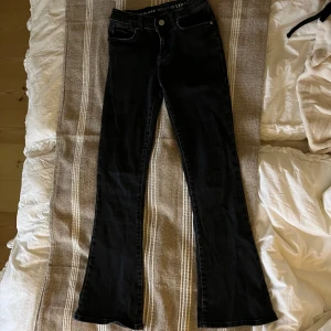 Svarta low flare jeans från Bik Bok - Snygga svarta low flare jeans från Bik Bok i storlek XS/31. De har en låg midja och äkta fickor med knapp och dragkedja framtill. Perfekta för en trendig look!
