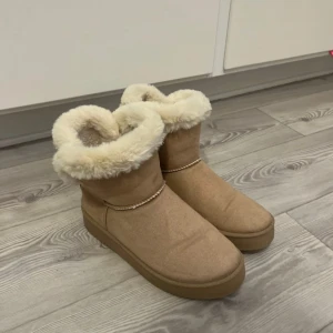Beige boots med fuskpäls - Säljer ett par mysiga beige boots med fuskpälsfoder. Sulan i har ramlat ut och därför behöver de köpas till men det är enkelt att hitta för billigt pris.