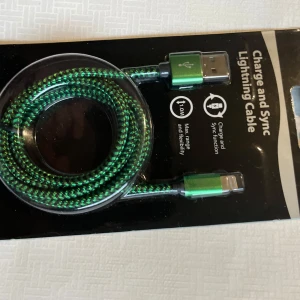 Grön laddnings- och synkkabel - Säljer en grön laddnings- och synkkabel med USB och Lightning-kontakter. Kabeln har en flätad design för extra hållbarhet och flexibilitet. Perfekt för att ladda och synkronisera dina enheter.