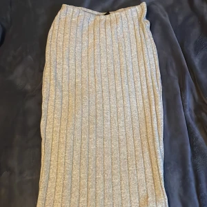 Grå ribbad långkjol - Snygg grå långkjol med ribbad design. Perfekt för en stilren look. Kjolen har en enkel och elegant form som passar till många olika tillfällen.