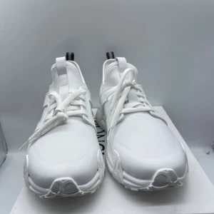 Moncler skor - Snygga vita sneakers från Moncler med en modern design. Skorna har snörning och en svart detalj på hälen med Moncler-loggan. Perfekta för en stilren look. Skorna är äkta finns kvitto det är helt nya köpta från farfetch hojta till för fler frågor och funderingar