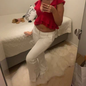 Röd volangtopp - Säljer en snygg röd volangtopp med djup v-ringning. Toppen har korta ärmar och en trendig volangdetalj som ger en feminin touch. Perfekt för att piffa upp garderoben! Vid fler frågor kan vi ta det privat:)