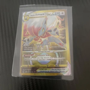 Hisuian Zoroark VSTAR Pokémonkort - Säljer ett Hisuian Zoroark VSTAR Pokémonkort med 270 HP. Kortet har attacker som Ticking Curse och förmågan Phantom Star. Det är en del av VSTAR-serien och har en glänsande finish.