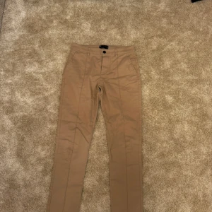 Beige chinos från ASOS Design - Snygga beige chinos från ASOS Design med en klassisk look. Byxorna har en normal passform och är tillverkade i en bomullsblandning för extra komfort. Perfekta för en stilren vardagslook.  Strl: W30/L32 Skick: bra skick Ord. Pris: 399 Säljes då de blivit små på mig  Din stil: spara inlägget så du inte missar denna kappa Inte din stil: Kolla min profil. Du kommer hitta något för alla kön och åldrar.