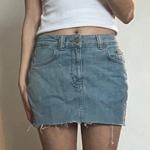 Blå jeanskjol - Säljer en snygg blå jeanskjol med rå kant och klassisk femficksdesign. Kjolen har en knapp och dragkedja framtill samt hällor för bälte. Perfekt för en avslappnad stil. Pris kan diskuteras ✨