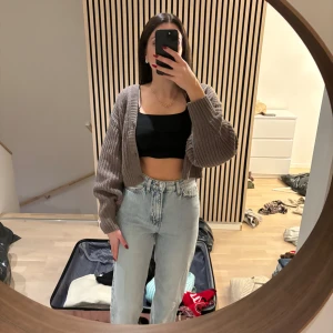 Visa Jeans - Säljer en mysig brun stickad kofta med långa ärmar. Perfekt för kyligare dagar och kan enkelt matchas med olika outfits. Koftan har en croppad design som ger en modern look.