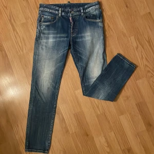 Blå jeans från Dsquared2 - Snygga blå jeans från Dsquared2 med en klassisk femficksdesign och knappar i gylfen. Jeansen har en lätt slitning för en trendig look och en läderpatch med logotyp baktill. Perfekta för en stilren vardagsoutfit. Köpte på Zalando Lounge för 1600kr. Tyvärr har lappen på baksidan gått sönder vilket gör att ja drar ner priset. Använda få tal gånger (ca 5 gånger) storlek 14y junior