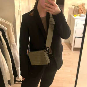 Axelremsväska - Snygg väska från carin wester. Grön/khaki färg med ormskinn liknande material. Justerbart axelband. Använt fåtal gånger💕