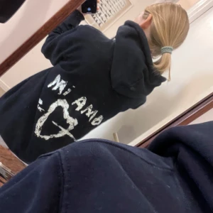 Svart hoodie från Mira Paris - Säljer en mörkblå hoodie från Mira Paris i storlek S. Orginalpris: 1 100kr. Den har en cool text 'Mi Amor' med ett hjärta och pil på baksidan. Endast använd ca 2 ggr. Passar perfekt för höst och vinter!💕