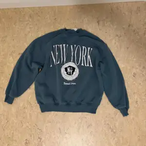 Säljer en snygg och bekväm mörkblå sweatshirt med stort 'New York' tryck på framsidan. Tröjan har långa ärmar och är perfekt för en avslappnad stil. Den är i bra skick och passar perfekt för höst och vinter.