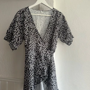 Klänning med blommor  - Fin korsad klänning med blommor på. Vet tyvärr inte vart den kommer ifrån men står i storlek L. Skulle mer säga S eller M