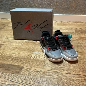 Jordan 4 - Säljer ett par snygga Nike Air Jordans i grått och svart med röda detaljer. Skorna har en cool design med snörning och en vit sula. Perfekta för både vardag och fest! De är i nyskick och kommer med originalkartong och är helt nya (oanvända)