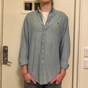 Ralph Lauren jeansskjorta   - Säljer en ljusblå jeansskjorta från Ralph Lauren. Skjortan är i väldigt fint skick och killen på bilden är 180. Hör av er vid frågor☺️