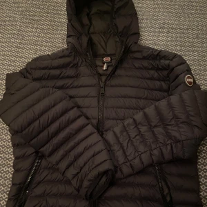 Svart dunjacka från Colmar - Säljer en stilren svart dunjacka från Colmar med huva och dragkedja. Jackan har ett quiltat mönster och långa ärmar. Allt är såklart äkta. Perfekt för kyligare dagar. Jackan är i storlek XL men sitter som en L/M, den har inga defekter, och har används skonsamt och försiktigt. Om du har frågor eller funderingar kring produkten så skriv till oss så bemöter vi dig när vi har tid. Priset är ej hugget i sten.