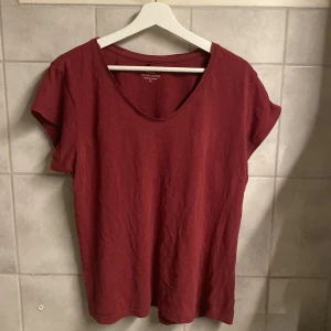 Röd t-shirt från Basic Collection - Säljer en röd t-shirt från Basic Collection i ekologisk bomull. Den har en enkel design med korta ärmar och rund hals. Perfekt för en avslappnad stil.