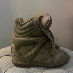 Beige sneakers med kardborreband - Snygga beige sneakers med hög design och kardborreband. Tillverkade i mocka med vadderad plös och häl för extra komfort. Perfekta för en trendig look. Från isabel marant. 