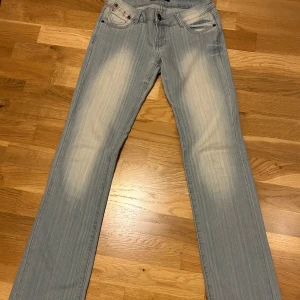 Ljusblå jeans med broderad detalj - Snygga ljusblå Bestyled jeans med en broderad detalj på bakfickan. Mycket låg midja. Storlek XS. Midjemått 35 cm rakt över. Innerbenslängd 82 cm. Det är dessa bilder jag har.