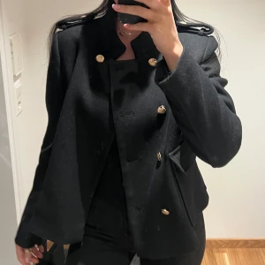 Svart jacka från Zara - Snygg svart kavaj från Zara med guldknappar och axelvaddar. Perfekt för en stilren look. Kavajen har en klassisk design med långa ärmar och en elegant passform.
