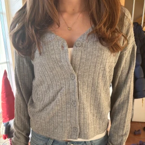 Grå ribbad kofta - Säljer en stilren grå ribbad kofta med knappar framtill. Perfekt för lager-på-lager och passar till många olika outfits. Fin både öppen, knäppt eller halv knäppt💕