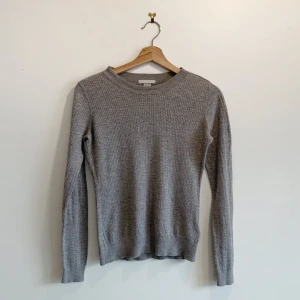 Grå stickad tröja från H&M - Säljer en stilren grå stickad tröja från H&M. Tröjan har en rund halsringning och långa ärmar, perfekt för kyligare dagar. Materialet är en blandning av viskos och polyamid vilket ger en mjuk och bekväm känsla. Passar utmärkt till både jeans och kjol.