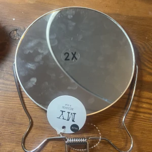 Förstoringsspegel från MY - Praktisk förstoringsspegel från MY med två sidor: 2x och 1x förstoring. Perfekt för smink och detaljarbete. Spegeln har en stabil metallram och kan enkelt ställas på bordet. Helt oanvänd jag tvättar den noga innan jag skickar den, snälla köp så mycket du vill jag sparar till en häst och dom är riktigt dyra så jag säljer tills jag har råd snälla köp så mycket du behöver🤗