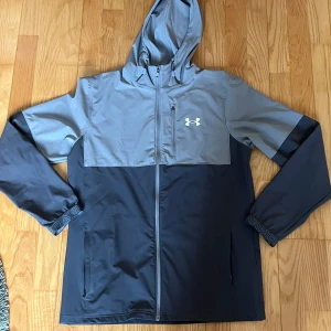 Under armour windbreaker storlek M - Jag säljer en knappt använd under armour windbreaker i storlek M. Perfekt nu under våren och till svalare sommar kvällar. 
