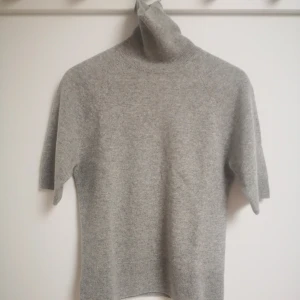 Grå kortärmad polotröja i 100% kashmir - Säljer en stilren grå kortärmad polotröja i 100% mjukt kashmir. Tröjan har korta ärmar och en klassisk polokrage, perfekt för lager-på-lager under kyligare dagar. Ett måste i garderoben. Nypris 1300 kr från HM Premium Quality. Personen på bilden är 174 cm. Ny! 