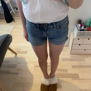 Blå jeansshorts från Cubus  - Snygga blå jeansshorts från Cubus med klassisk femficksdesign och uppvikta benslut. Perfekta för en avslappnad stil. De har en knapp och dragkedja framtill för enkel stängning.