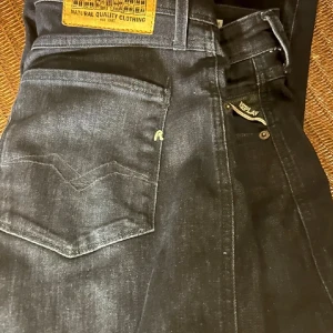 Mörkblå jeans från Replay - Snygga mörkblå jeans från Replay, modell Anbass. De har en slim fit passform och klassisk femficksdesign. Perfekta för en stilren look med dragkedja och knappstängning.