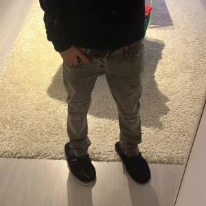 Grå jeans från Jack & Jones - Snygga grå jeans från Jack & Jones med slitna detaljer och en slim passform. Perfekta för en avslappnad stil med en modern stil. Storleken är 29/30, skicket på byxorna är 10/10 som är aldrig använda, priset kan diskuteras vid snabb affär. Hör av er vid frågor 