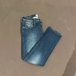 Replay anbass jeans  - Snygga Replay anbass jeans femficksdesign och ljusa slitningar. Perfekt till dig som har en avslappnad stil😎 som du ser finns det ett litet hål på höger ben (går lätt att lappa över inne från byxan) 