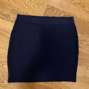 Mörkblå kjol - Snygg mörkblå kjol i en klassisk och stilren design. Perfekt för en elegant look. Kjolen har en enkel passform och är lätt att matcha med olika toppar.