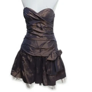 Brun axelbandslös klänning från Laona - Snygg brun axelbandslös klänning från Laona i storlek M. Tillverkad i 100% polyester med en elegant rosett i midjan och omlott-design. Perfekt för festliga tillfällen.