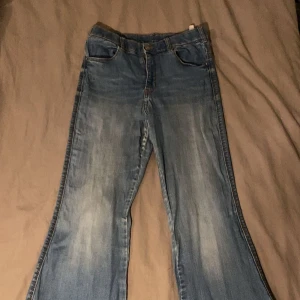 Blå bootcut jeans - Snygga blå bootcut jeans med klassisk femficksdesign. De har en dragkedja och knapp framtill. Perfekta för en avslappnad stil.