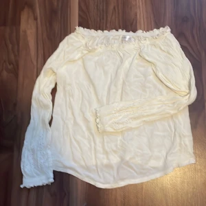 Vit blus med detaljer  - Säljer en vit off-shoulder blus då den är för stor för mig. Blusen är i storlek M och kommer från lager157. Den har diskreta mönster längre ned på ärmarna och är i mycket bra skick.