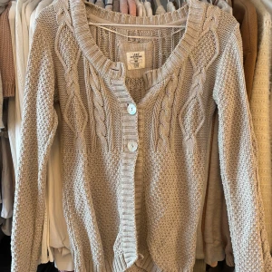 Beige stickad babydoll kofta - Säljer en mysig beige stickad  babydoll kofta från logg med flätmönster och stora knappar framtill. Det saknar en knapp längst upp men kan repareras lätt om man hittar någon liknande knapp. 💐💓 öppen för prisförslag 